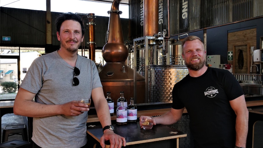 Two men are stading inside a whiskey distillery 