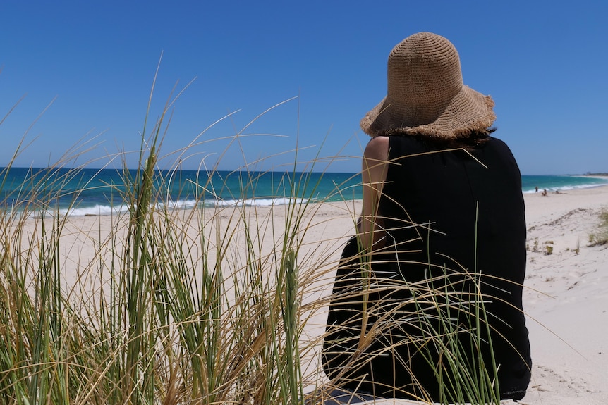 A woman sitting in the sand dunes.