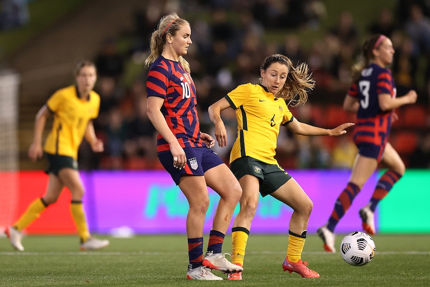 A Matildas defender rushes in to pressure an American player who plays the ball away quickly.