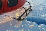 A helicopter, landed on a faint line in the snow, with a hole in it where David Wood fell through.