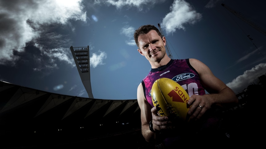 Patrick Dangerfield holds a football wearing his training singlet