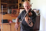 84 year old Norm Lambert playing his violin in his music room.