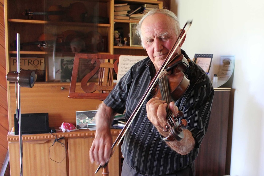 84 year old Norm Lambert playing his violin in his music room.