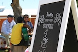 Banksia Beans Cafe coffee sign with detainee playing guitar in the background.