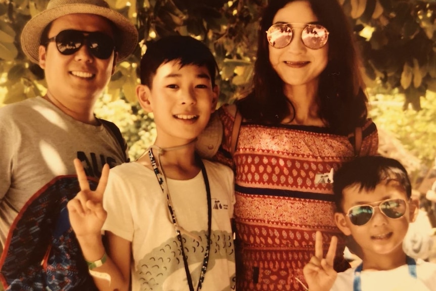 Tingting Wang with her husband and two boys smiling at the camera on holiday. 