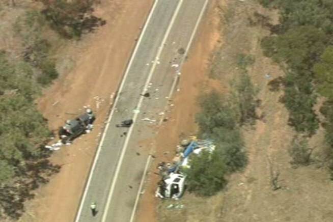 An aerial view of a car and a truck all smashed up and lying on their sides on a rural road