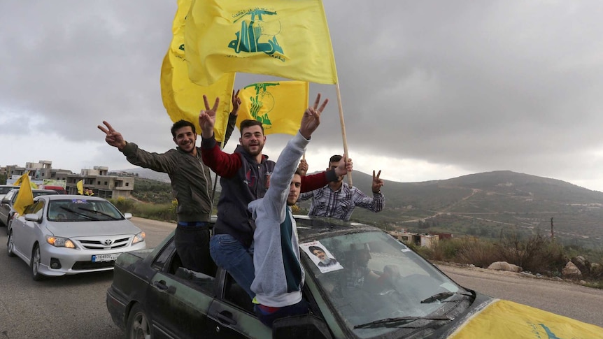 Supporters of Lebanon's Hezbollah wave flags and hold their fingers in peace signs.