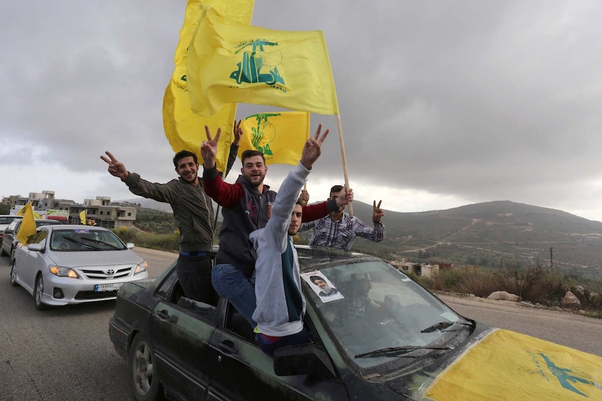 Supporters of Lebanon's Hezbollah wave flags and hold their fingers in peace signs.