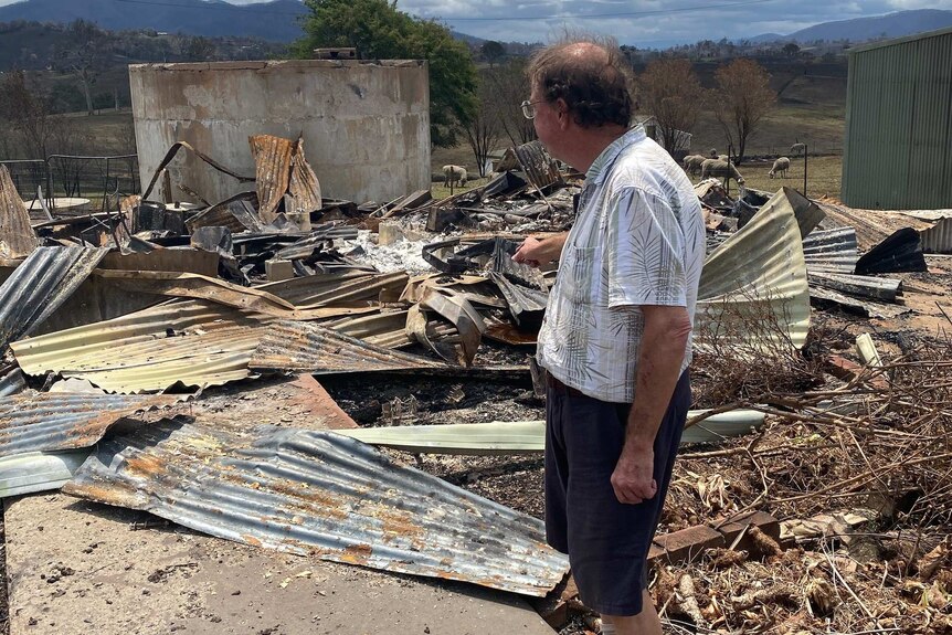 Dr Lee stands at the site of his burnt down practice, surrounded by tin and debris