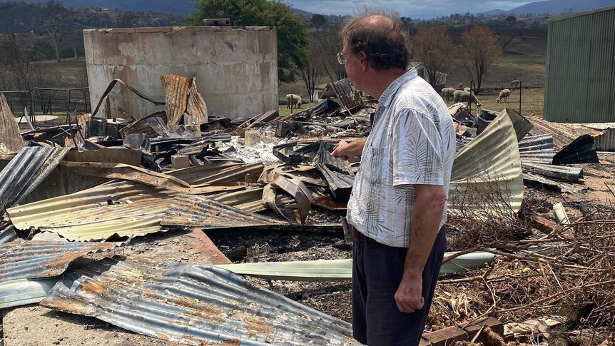 Dr Lee stands at the site of his burnt down practice, surrounded by tin and debris