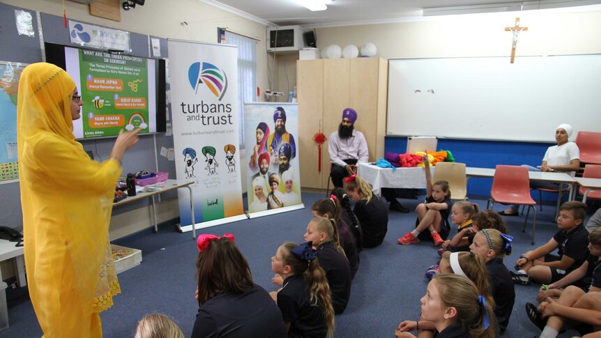 Students sit on the floor in classroom watching Sikh presentation