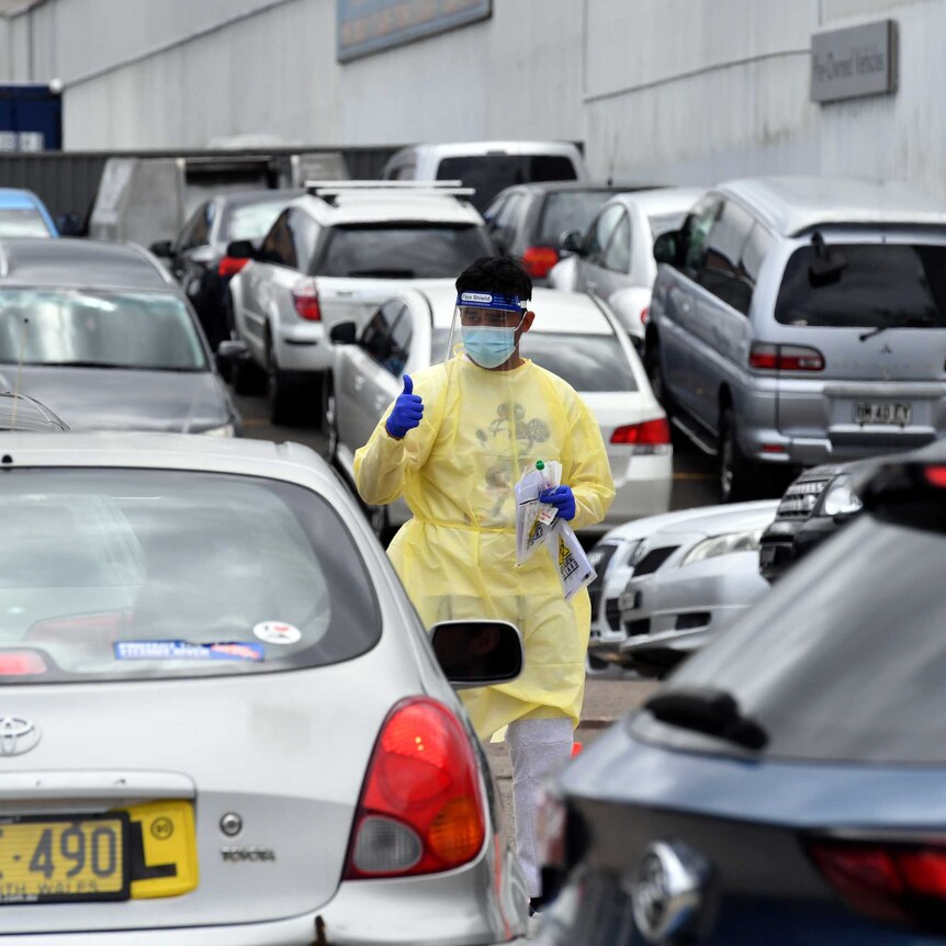 A health worker stands between cars at a covid testing station