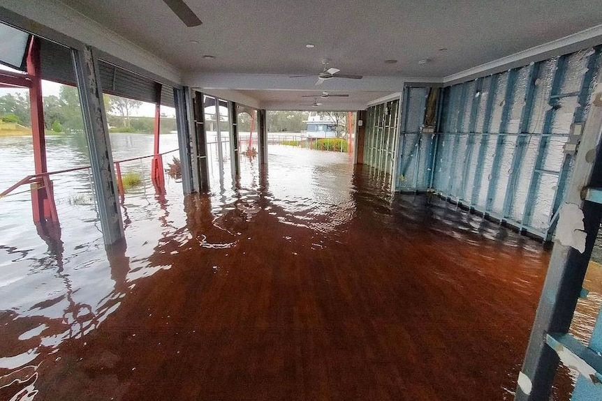 Brown floodwaters rush through the interior of a cafe.
