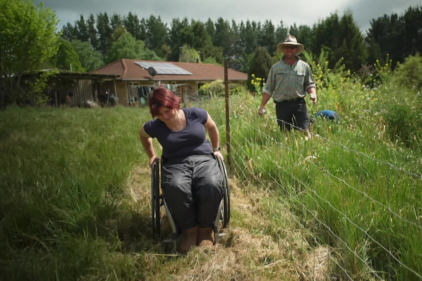 Image of a woman in a wheelchair with a man behind her gardening. 