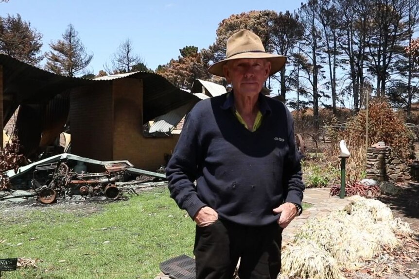 John Symons stands in front of his damaged property.