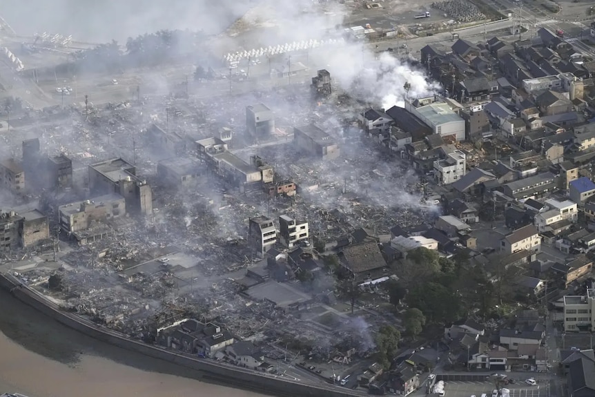 An aerial view of a damaged city and smoke from buildings