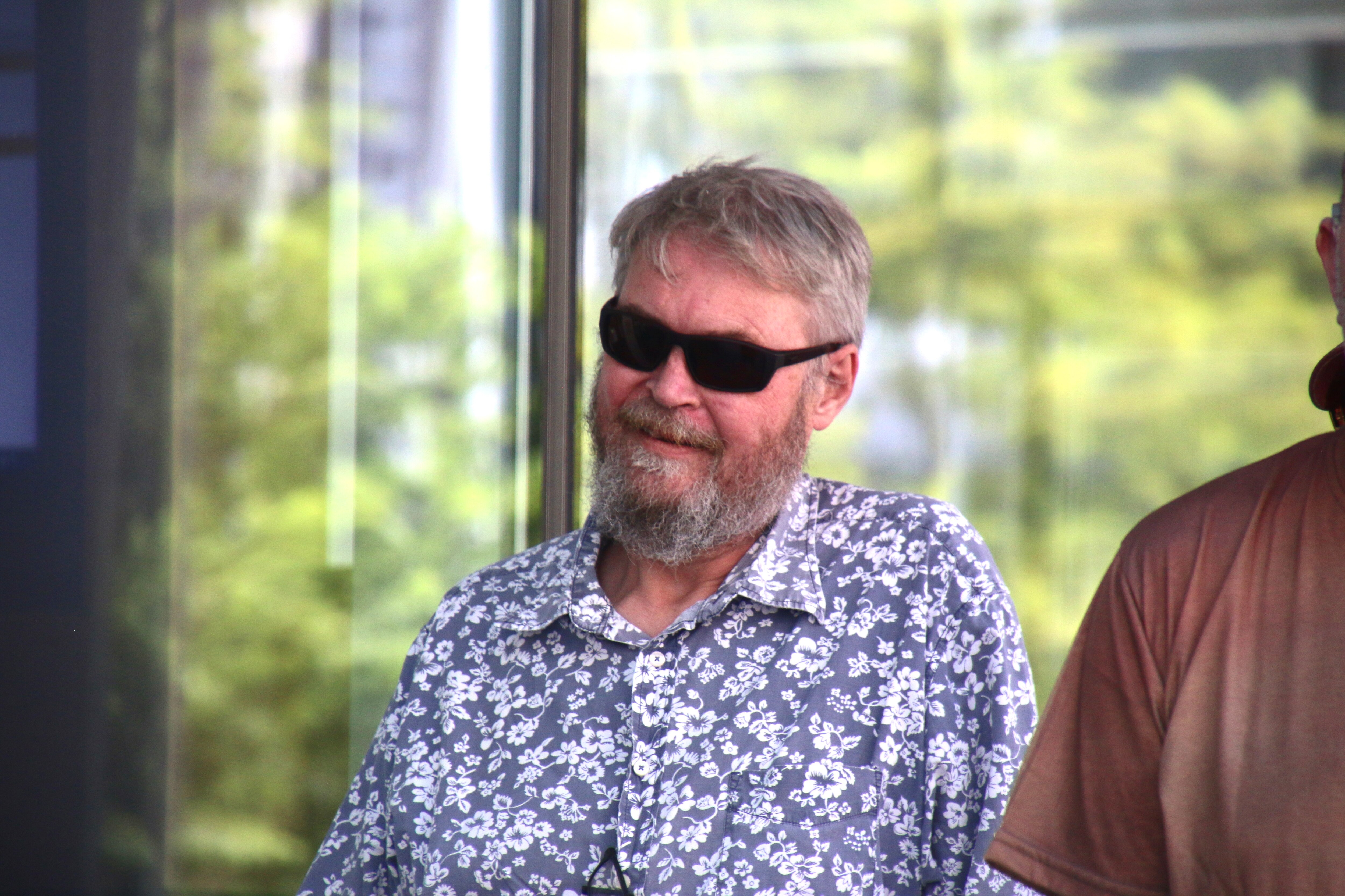 A man in dark glasses and a flowery shirt