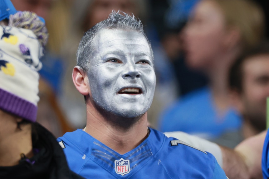 A fan with silver facepaint looks on during an NFL match