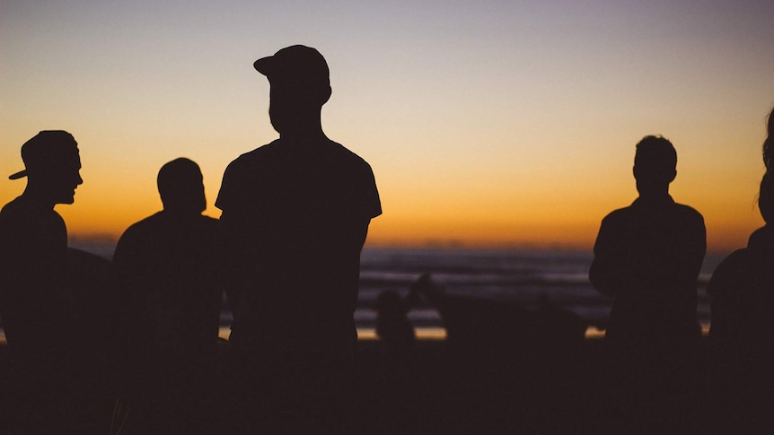 Silhouetted young people looking at the horizon at dusk