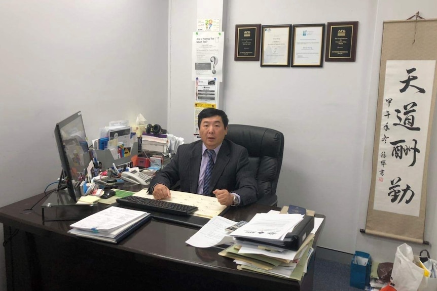 Oliver Zhang, an accountant in Sydney, sits behind his desk in his office.