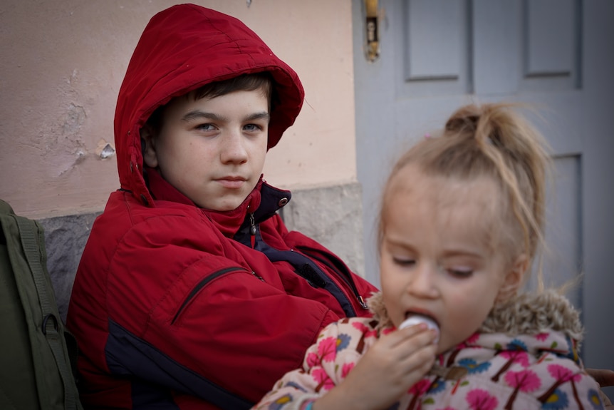 A young boy with blue eyes looks calmly at the camera