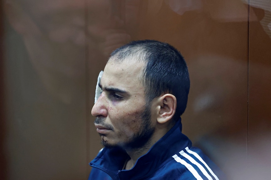 四名恐怖主义嫌疑人之一坐在莫斯科巴斯曼尼地区法院的玻璃隔间里。