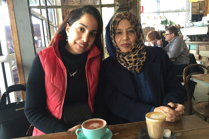 A young woman and her mother drinking coffee in a cafe.