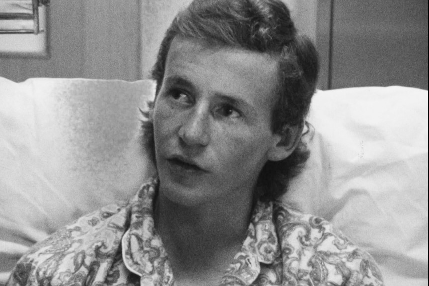 A black and white image of a young man in hospital