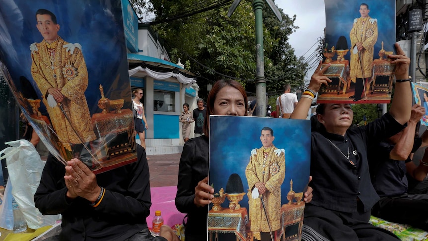 Well-wishers hold up pictures of Thailand's new King Maha Vajiralongkorn.