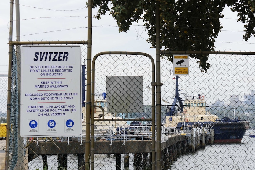 A locked gate in front of boats on the port water bears a 'Svitzer' sign.