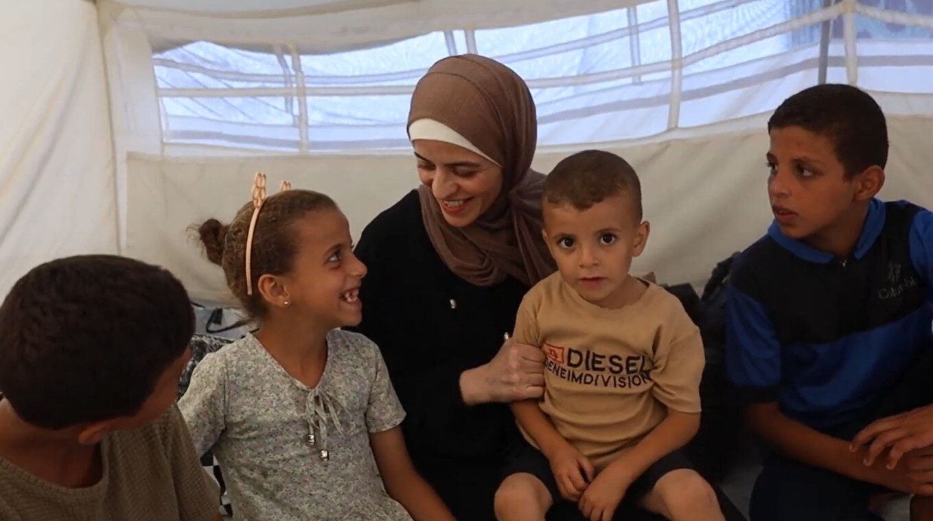 Mervat Sarhan smiles down at her daughter as she holds her son on her lap while speaking to her other two children.