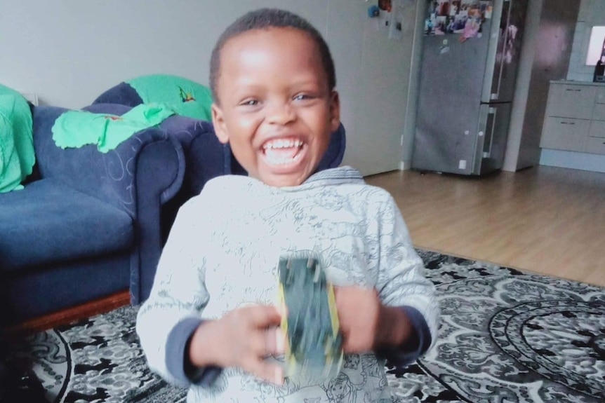 A young boy laughs and looks straight into the camera