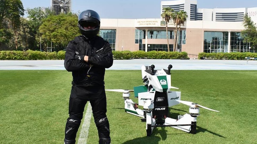 A pilot stands beside the Hoversurf Scorpion, a vehicle commissioned by Dubai police.