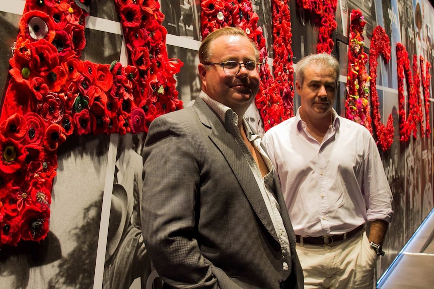 Tim and Chris Scott stand beside a wall of poppies at the Spirit of Anzac Centenary Experience in Sydney