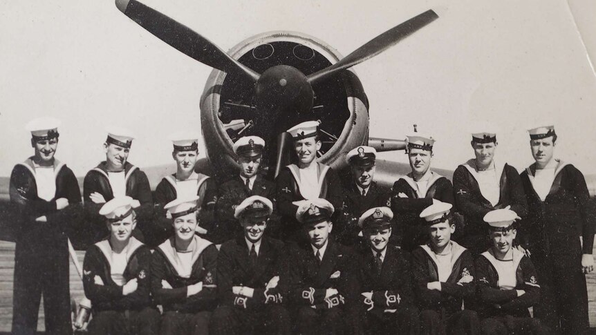 A black and white photo of sailors with an old aeroplane