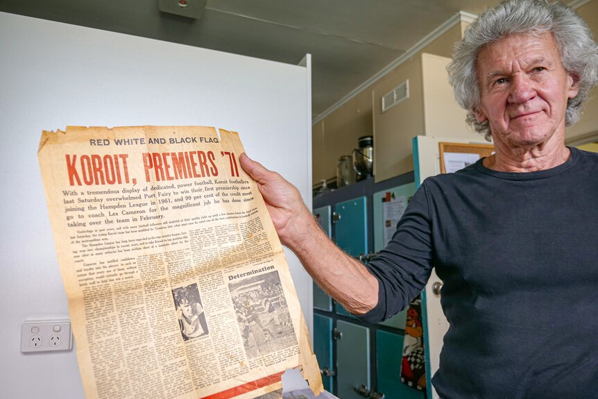 Les holds an aged newspaper clipping