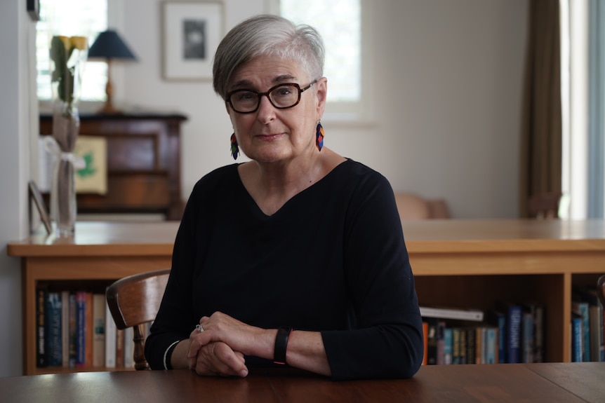 A woman sits at a table in her Perth home