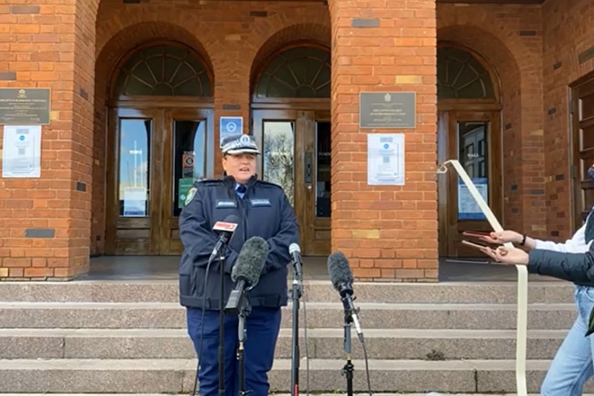 A police officer stands before a microphone at a press conference