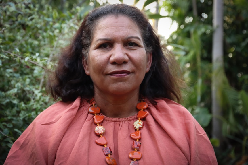 Portrait of a woman outside wearing a pink blouse.