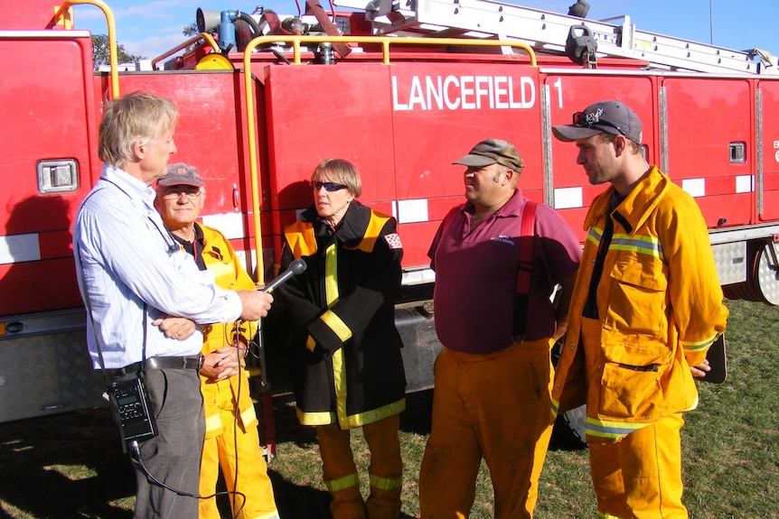 Tony Eastley interviews a group of firefighters after the 2009 Victoria bushfires.