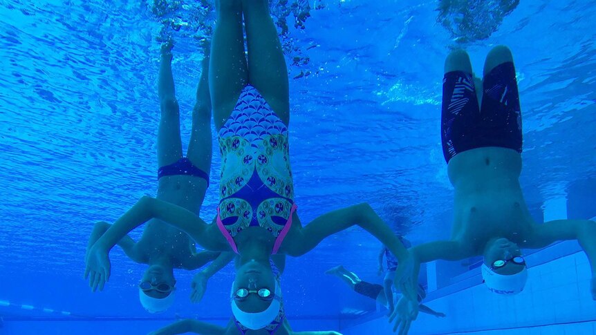 Two boys and a girl upside down underwater in Southport Aquatic Centre