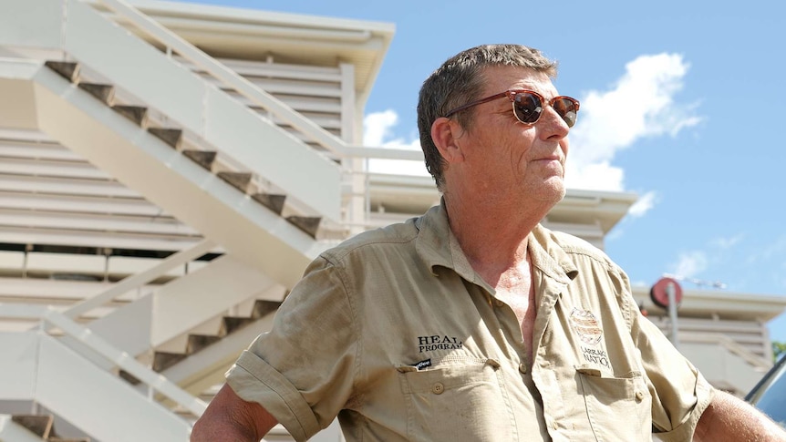 A photo of a man standing in front of a Darwin unit block wearing sunglasses.