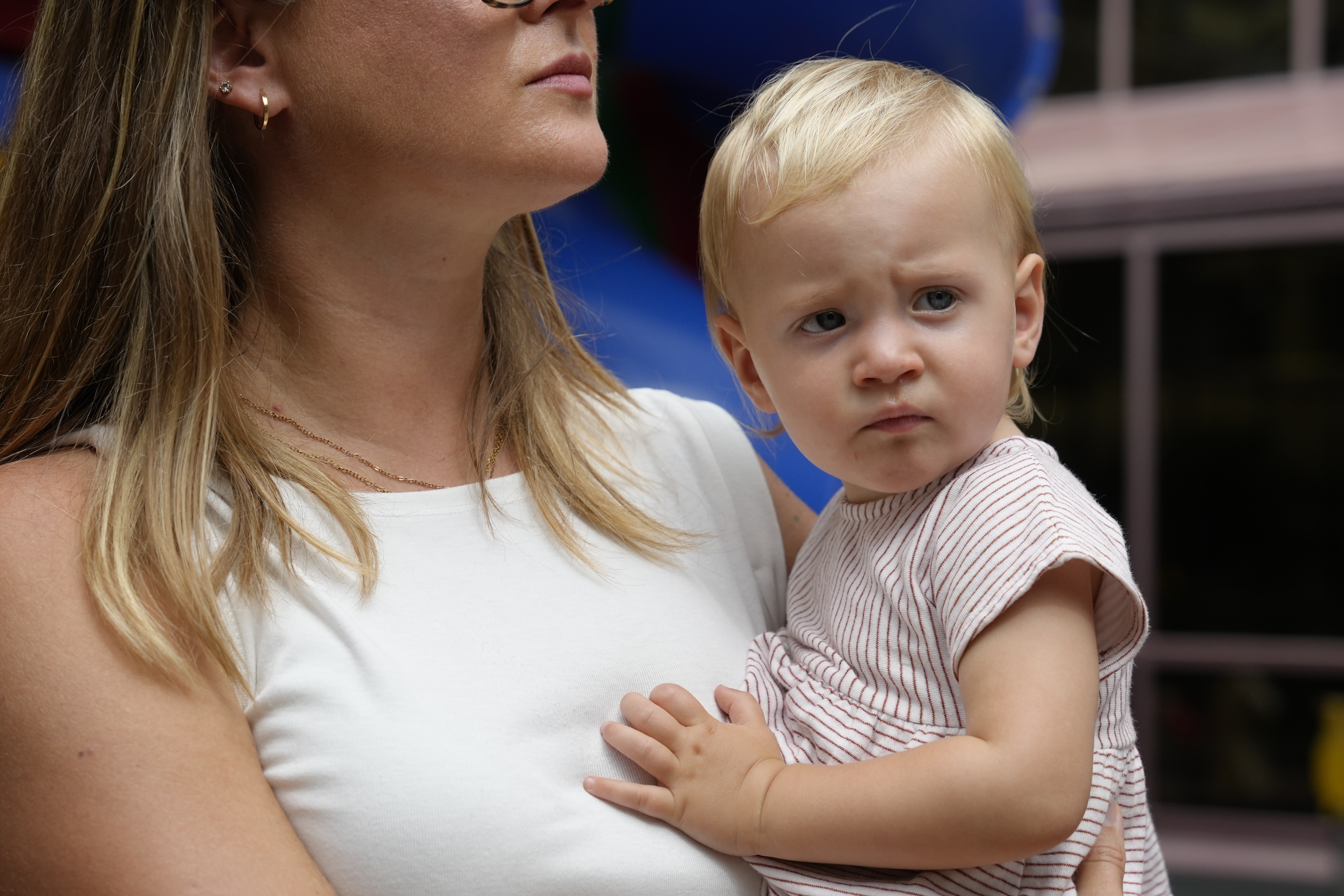 A toddler being held by her mother.