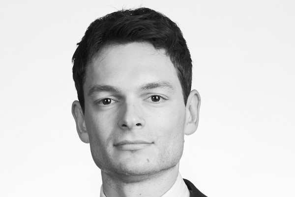 A young man with dark hair wearing a suit and tie.