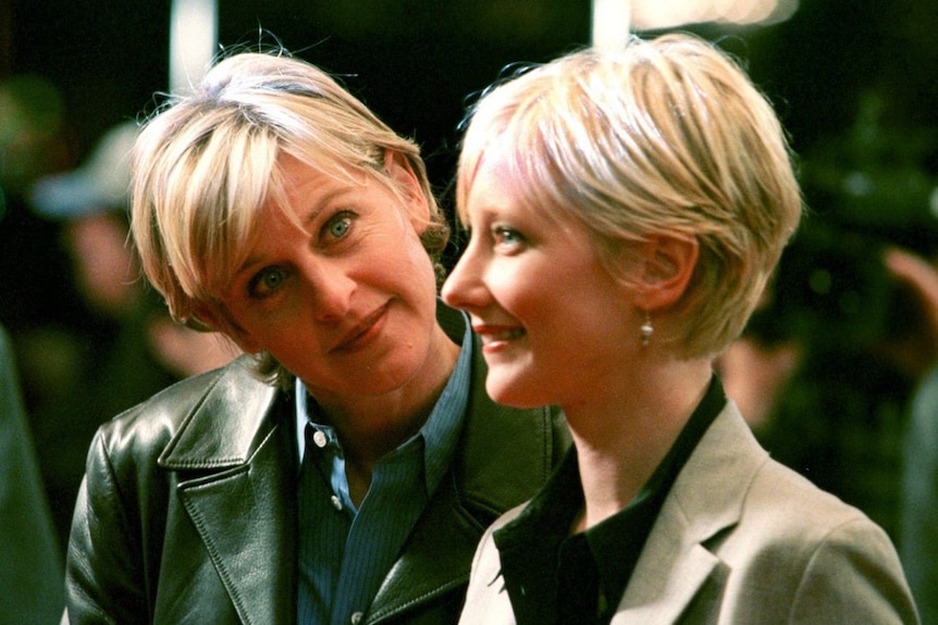 Ellen Degeneres cocks her head to the side and looks at Anne Heche as Heche smiles