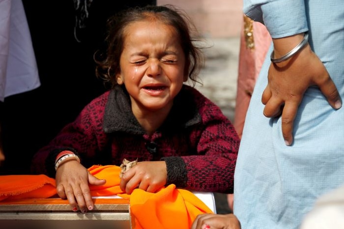 A small child sobs over a coffin