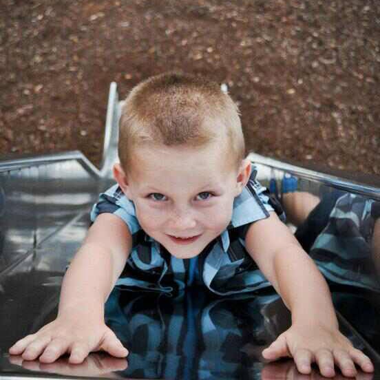 A young boy slides backwards down a slide.