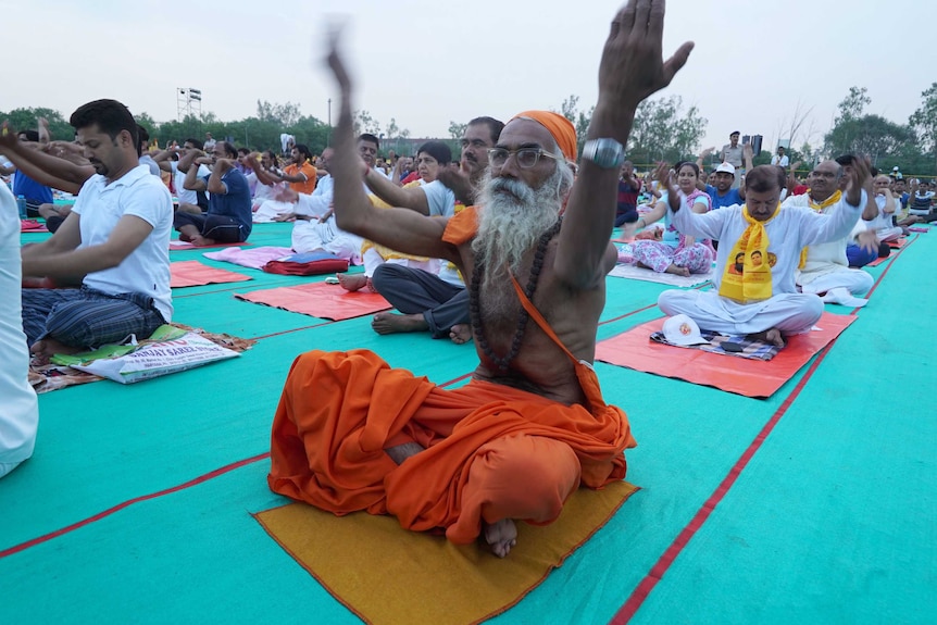 A man raises his hand during a mass yoga event in Faridabad
