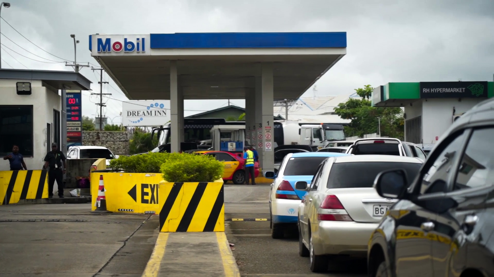 A line of cars waits to enter a petrol station with MOBIL signage