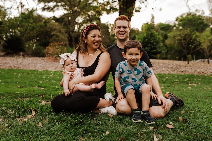 A family sitting on the grass smiling